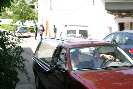 La madre saliendo de la vivienda y el coche funebre con el pequeno ataud